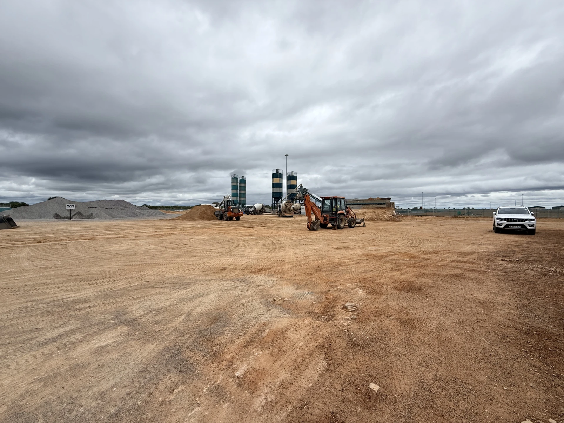 Active construction site with concrete batching plant and earthmoving equipment